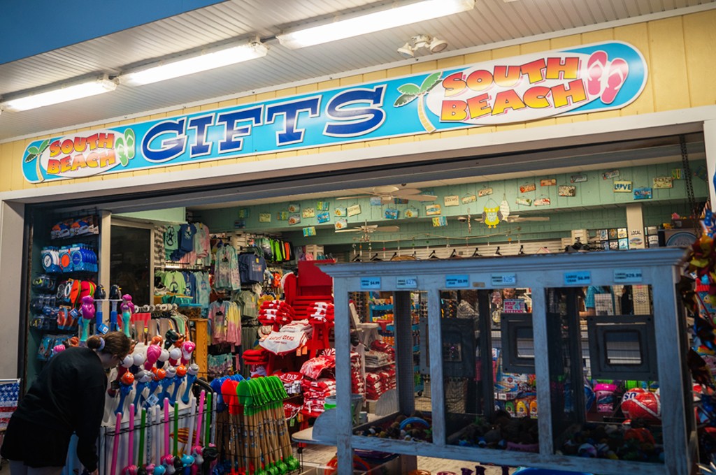 A man stands in front of a store, holding a sign.
