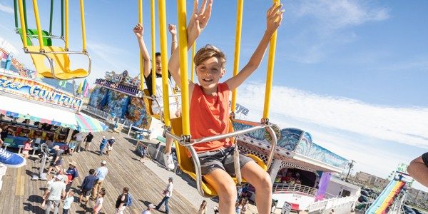 2 Kids riding on the the swings ride in the amusement park on Jenkinson's Boardwalk