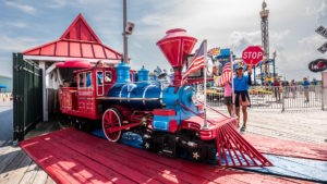 Passengers enjoy a ride on our train at Jenkinson's Boardwalk. Amusement park employee holds stop sign to warn visitors as train passes with riders